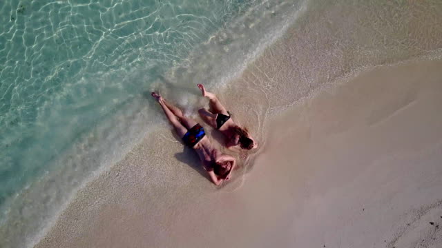 v04032-fliegenden-Drohne-Luftaufnahme-der-Malediven-weißen-Sandstrand-2-Personen-junges-Paar-Mann-Frau-romantische-Liebe-auf-sonnigen-tropischen-Inselparadies-mit-Aqua-blau-Himmel-Meer-Wasser-Ozean-4k