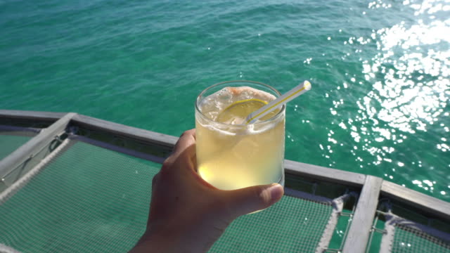 Hand-halten-gelb-leuchtenden-Sommer-tropischen-cocktail-mit-schönen-tropischen-Ozean
