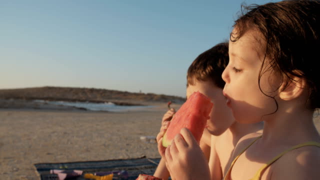 Drei-Kinder-essen-Wassermelonen-am-Strand