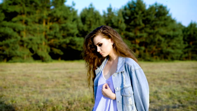 young-fashion-woman-is-wearing-summer-dress-and-jacket-is-walking-near-a-forest-in-summer-sunny-evening