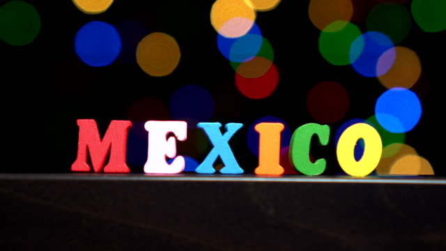 Colorida-palabra-\"México\"-de-Letras-de-madera-multicolor-frente-fondo-bokeh-de-Resumen-luces-borrosa