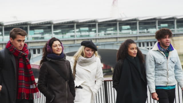 Friends-Walking-Along-South-Bank-On-Winter-Visit-To-London