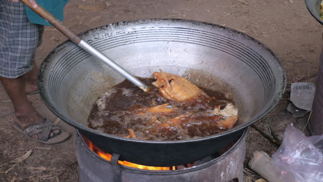 Nahaufnahme-eines-Mannes-gebratenen-Fisch-aus-einem-großen-Wok-Kochen