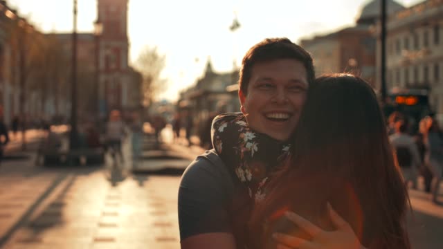 A-guy-meets-a-girl-walking-down-the-street-and-gives-her-a-hug,-close-up