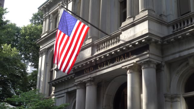 An-American-flag-waving-in-front-of-the-facade-of-a-building-in-Boston