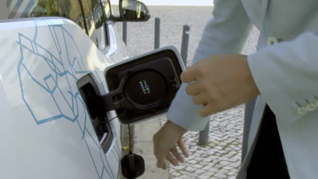 Close-up-of-man-connecting-cable-charger-to-electric-car