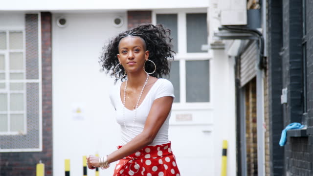 Modisch-junge-schwarze-Frau-tragen-rote-Polka-Dot-Hosen-auf-der-Straße-tanzen