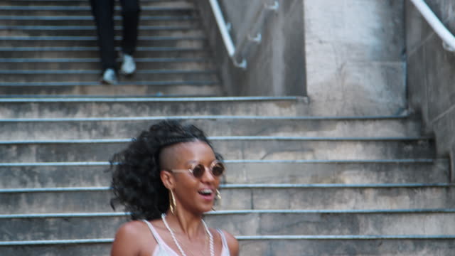 Fashionable-young-black-woman-wearing-sunglasses-walking-down-stairs-in-city-street,-close-up