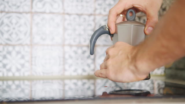 Kaffee-Zubereitung.-Video-des-Mannes-Hand-Kniff-\"Mokka\"-Kaffeemaschine-Topf-und-auf-moderne-gläserne-Küche-Lochfraß-Kochfeld.-Zubereitung-von-Speisen-in-der-modernen-Küche-Konzept-4K-Filmmaterial.
