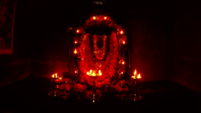 Altar-of-godess-Kali-Ma-human-sculls-with-flowers-statue-decorated-with-garland-and-burning-candles