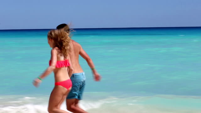 Young-couple-running--on-caribbean-beach
