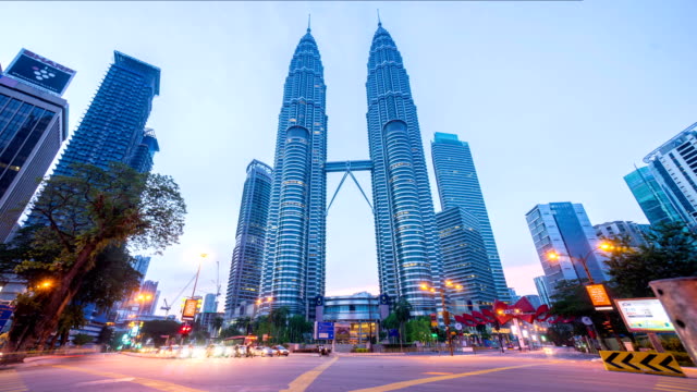 Night-to-day-4k-time-lapse-of-junction-traffic-light-in-front-of-Suria-KLCC-with-Petronas-Towers.