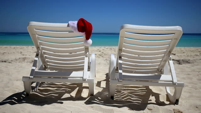 Santa-Claus-Hat-on-sunbed-near--tropical-calm-beach