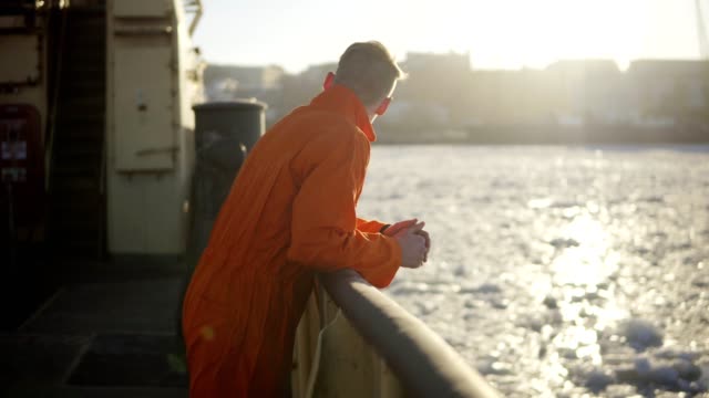 Junger-Mann-in-orange-Uniform-Reisen-an-Bord-des-Schiffes-im-Winter.