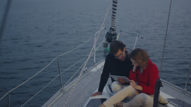 Pärchen-setzt-Tablet-auf-einer-Yacht-im-Meer-ein.