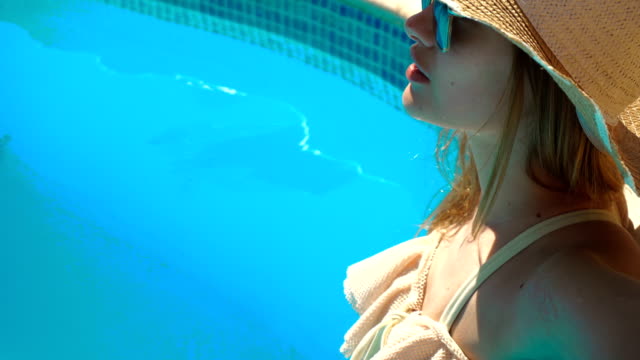 ein-junges-Mädchen-mit-einem-Hut-und-Brille-steht-in-einem-Badeanzug-im-Poolwasser