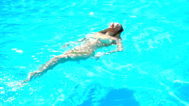 Junge-Mädchen-in-Gläsern-schwimmt-auf-dem-Rücken-in-einem-blauen-pool
