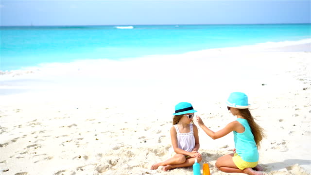 Kids-applying-sun-cream-to-each-other-on-the-beach.-The-concept-of-protection-from-ultraviolet-radiation