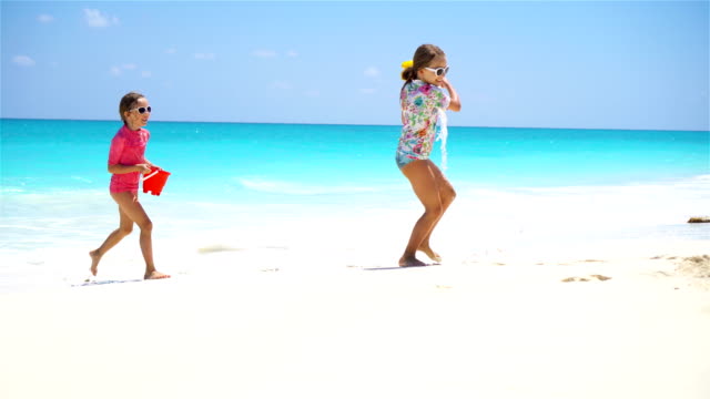 Entzückende-kleine-Mädchen-viel-Spaß-zusammen-auf-weißen-tropischen-Strand