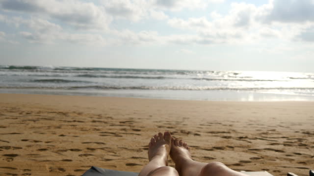 Weibliche-Füße-gegen-das-Meer-zu-spielen.-Beine-der-schönen-jungen-Frau,-die-am-Ufer-des-Meeres-in-den-Sommerferien-entspannende-Reise.-Gesichtspunkt-der-sexy-Mädchen-liegen-und-Sonnenbaden-am-Strand.-Nahaufnahme