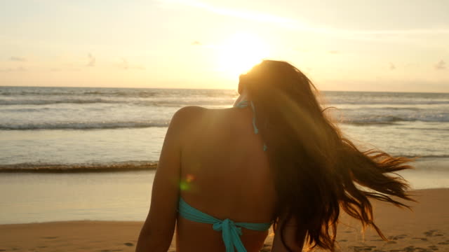 Schöne-junge-Frau-im-Bikini-stehen-am-Meer-bei-Sonnenuntergang.-Attraktive-sexy-Mädchen-mit-langen-Haaren-posiert-auf-der-Meer-Küste-bei-Sonnenaufgang.-Frau-am-Strand-und-genießen-Leben-in-Urlaub.-Nahaufnahme
