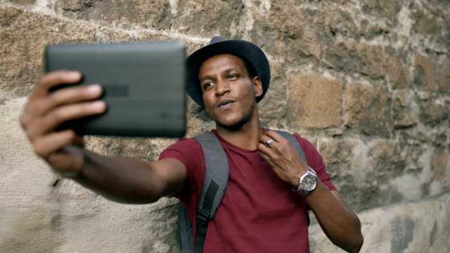 Glücklich-afrikanischer-amerikanischer-Tourist-Mann-mit-online-video-Chat-mit-Tablet-PC-unterwegs-in-Europa