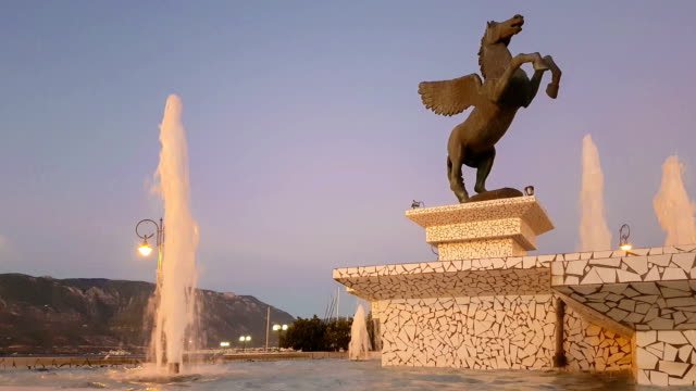 Korinth,-Griechenland,-5.-Oktober-2017.-Zentraler-Platz-von-Korinth-in-Griechenland-mit-Pegasus-Statue-gegen-einen-wunderschönen-Sonnenuntergang.