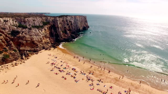 Beautiful-cliffs-and-sandy-beach-with-resting-people-in-Portugal,-Praia-do-Beliche,-Sagres-aerial