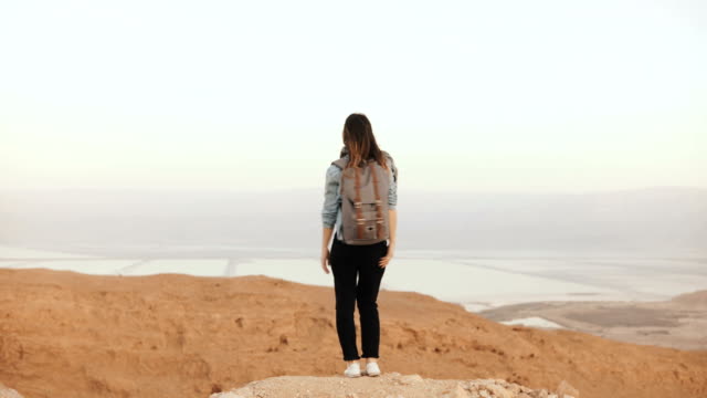 Girl-at-mountain-view,-jumping-with-arms-wide-open.-Pretty-European-woman-happy-and-excited.-Happiness.-Israel-desert-4K