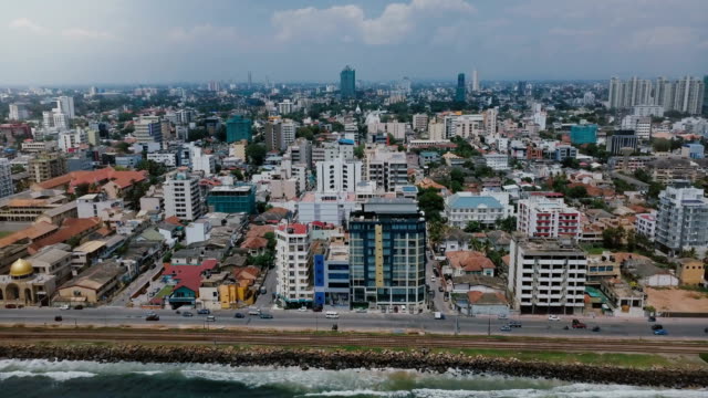 Drone-zooming-out-above-Colombo,-Sri-Lanka-panorama.-Aerial-view-of-Asian-resort-town,-modern-buildings-and-ocean-waves