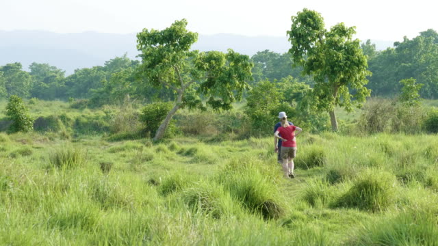 Couple-walking-in-rainforest-park-in-Chitwan,-Nepal.