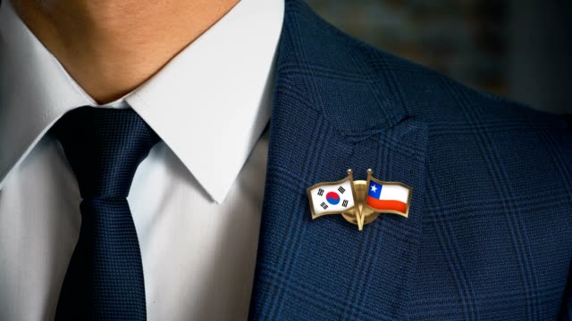 Geschäftsmann-zu-Fuß-in-Richtung-Kamera-mit-Freund-Land-Flaggen-Pin-Südkorea---Chile