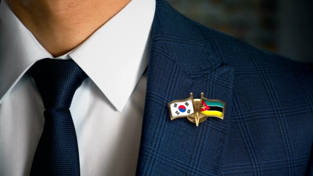 Geschäftsmann-zu-Fuß-in-Richtung-Kamera-mit-Freund-Land-Flaggen-Pin-Südkorea---Mosambik