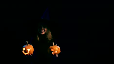 Girl-wearing-black-witch-hat-holding-jack-o'-lanterns