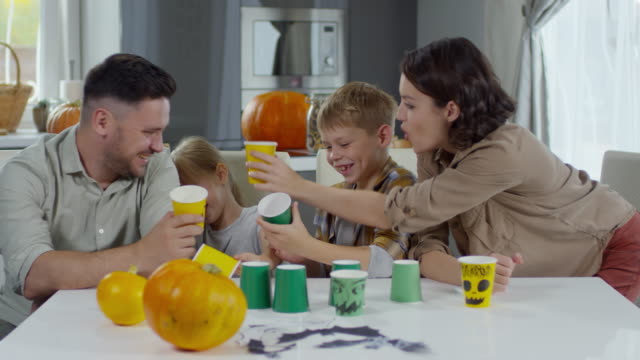 Glückliche-Familie-mit-Halloween-Cups-spielen