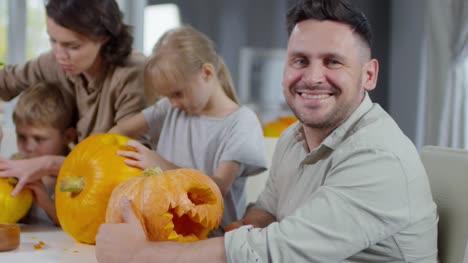 Man-Smiling-at-Camera-while-Making-Halloween-Pumpkins-Together