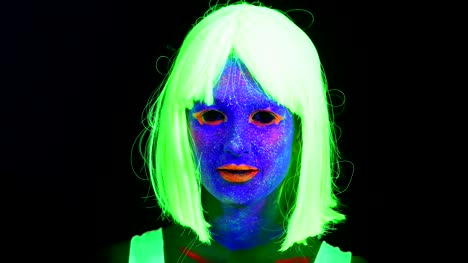 Woman-with-UV-face-paint,-wig,-glowing-clothing-portrait-turnaround-toward-camera,-face-close-up-of-make-up.-Caucasian-woman.-.