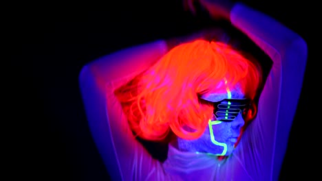 Woman-with-UV-cyborg-face-paint,-wig,-glowing-clothing-portrait-dancing-hard,-turn-around-shot.-Asian-woman.-.