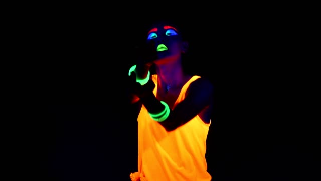 Woman-with-UV-face-paint,-glowing-clothing,-glowing-bracelet-in-front-of-camera,-half-body-shot.-Asian-woman.-.