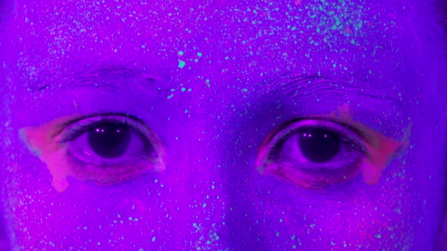 Closeup-woman-eyes-with-fluorescent-make-up,-creative-makeup-look-great-for-nightclubs.-Halloween-party,-shows-and-music-concept---slow-motion-video