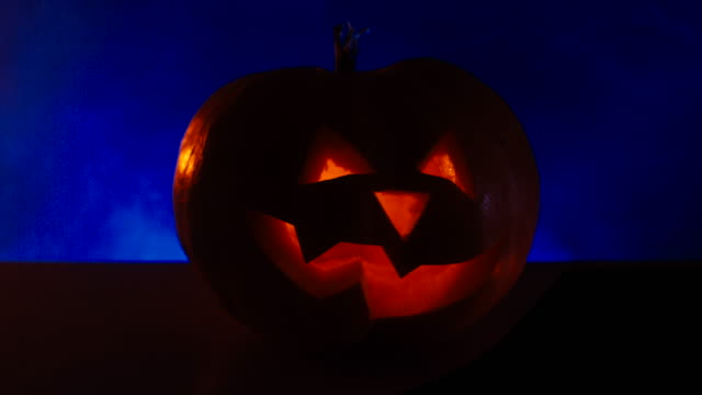 CINEMAGRAPH---CU-Halloween-tallado-CALABAZA-Jack-o-Lantern-con-velas,-niebla-en-el-fondo