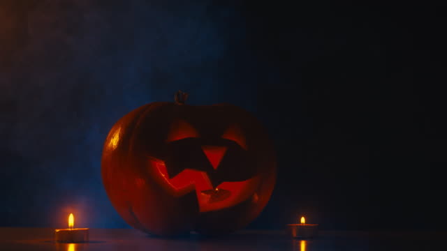 CINEMAGRAMM---CU-Halloween-geschnitzten-Kürbis-Jack-o-Laterne-mit-Kerzen,-Nebel-im-Hintergrund