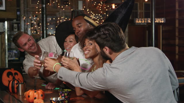 Friends-enjoying-a-Halloween-party-at-a-bar-making-a-toast,-shot-on-R3D