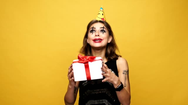 Displeased-strange-woman-with-holiday-cap-smiling-and-throwing-gift-isolated-over-yellow