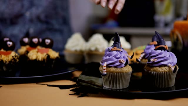 Cupcake-mit-Hut-und-Beine-Puderzucker-dekorieren.-Muffin-wie-Hexe.-Halloween-Konzept