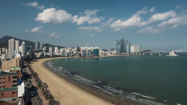 Haeundae-Beach-at-Busan-city,-South-Korea.-Time-lapse-of-car-traffic,-clouds,-walking-people-and-waves