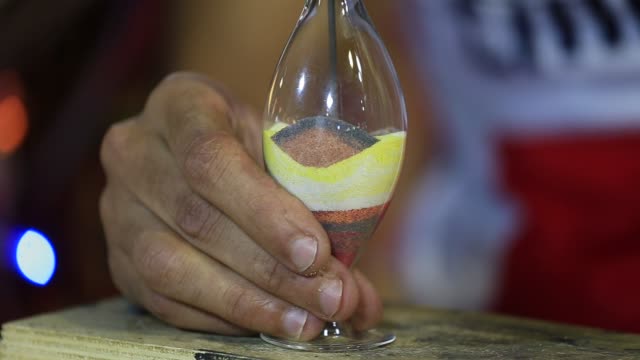 Man-shows-his-skills,-creating-a-souvenir-of-colored-sand-in-glass-vase.-Egypt