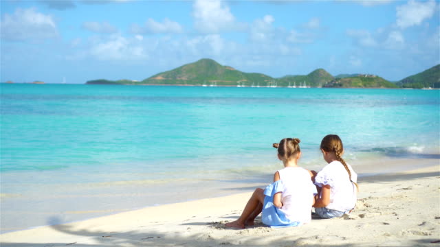 Dos-niñas-felices-tienen-un-montón-de-diversión-en-tropical-playa-jugando-con-arena