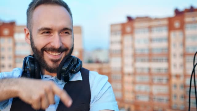 Close-up-face-of-cheerful-male-DJ-with-headphones-on-neck-having-fun-dancing-and-enjoying-party