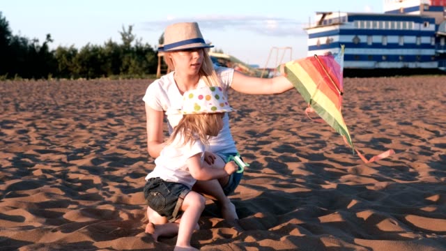 Schöne-Blondine-in-einem-Hut-Mutter-und-Tochter-startet-einen-Kite-am-Strand.